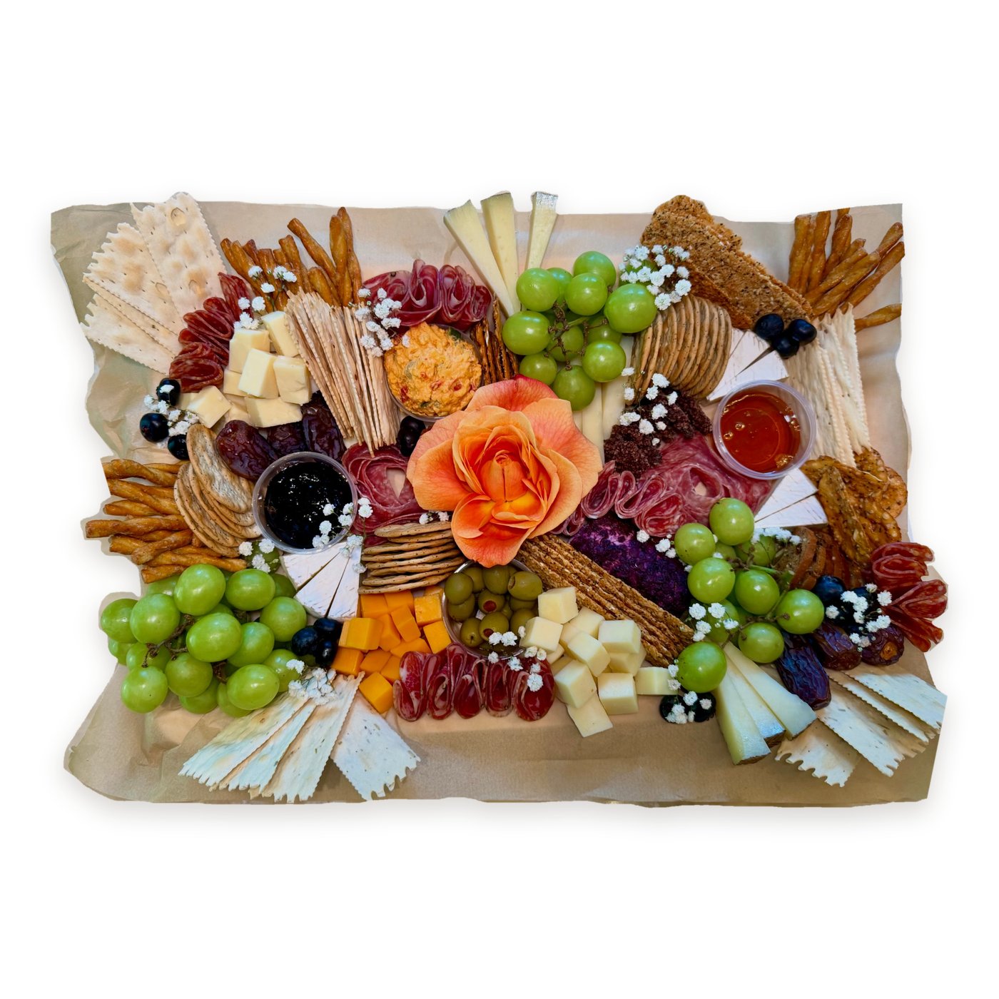 Rectangular charcuterie board with a peach rose, salami, cheeses, green grapes, crackers and breadsticks